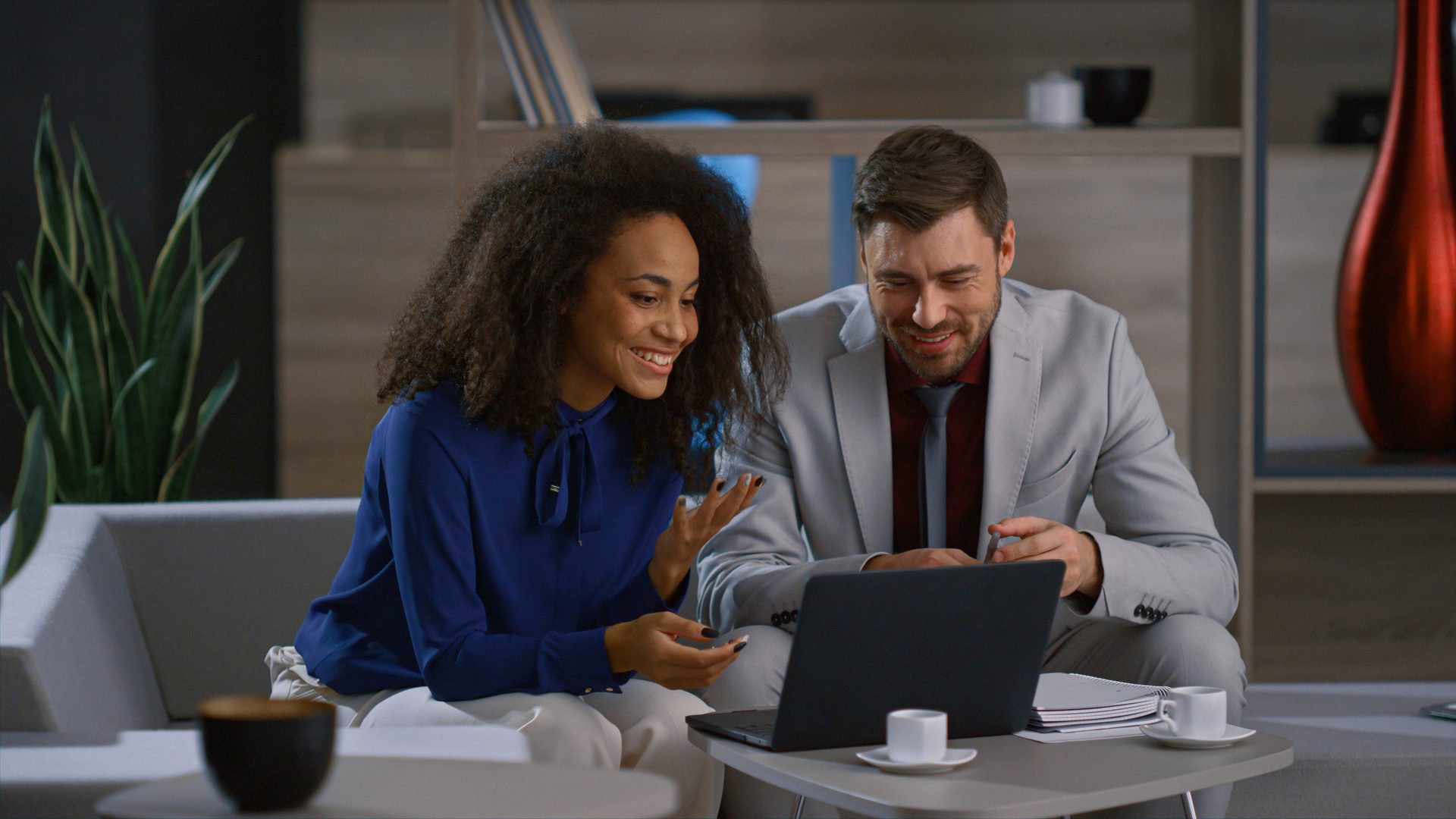 Two cafe owners reviewing their business together on a laptop at the counter
